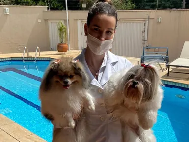 Veterinária com dois cães no quintal durante atendimento em domicílio