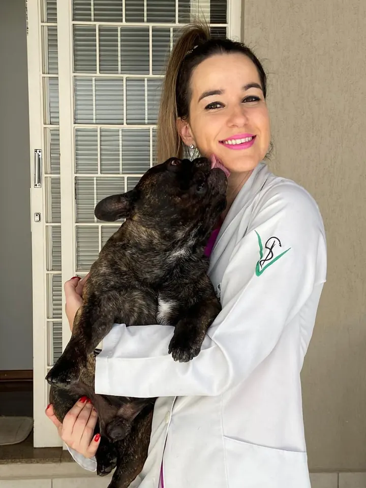 Dra. Juliana Riedo sorrindo com um buldogue francês no colo